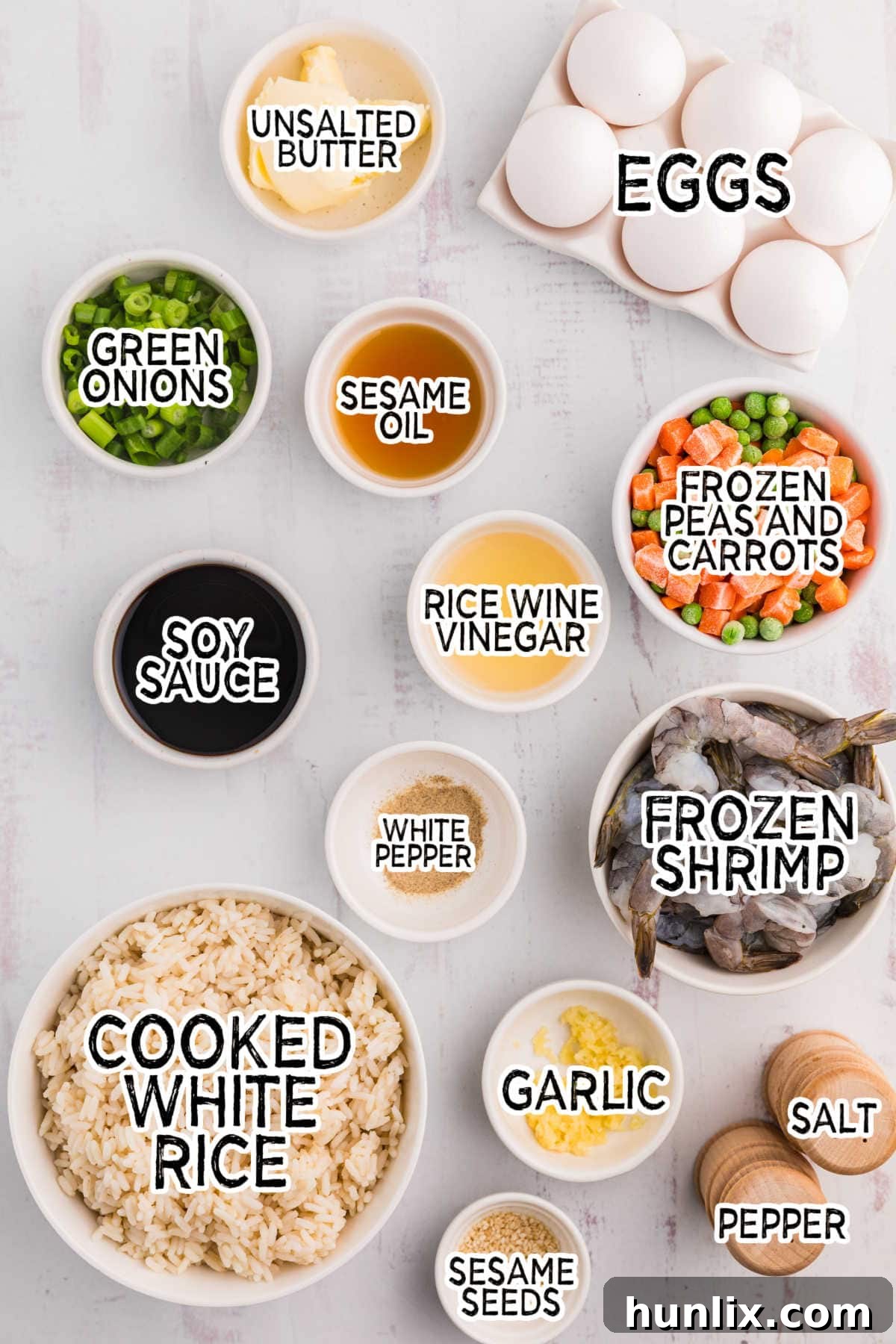 A selection of fresh ingredients neatly arranged on a white background, ready for shrimp fried rice preparation.