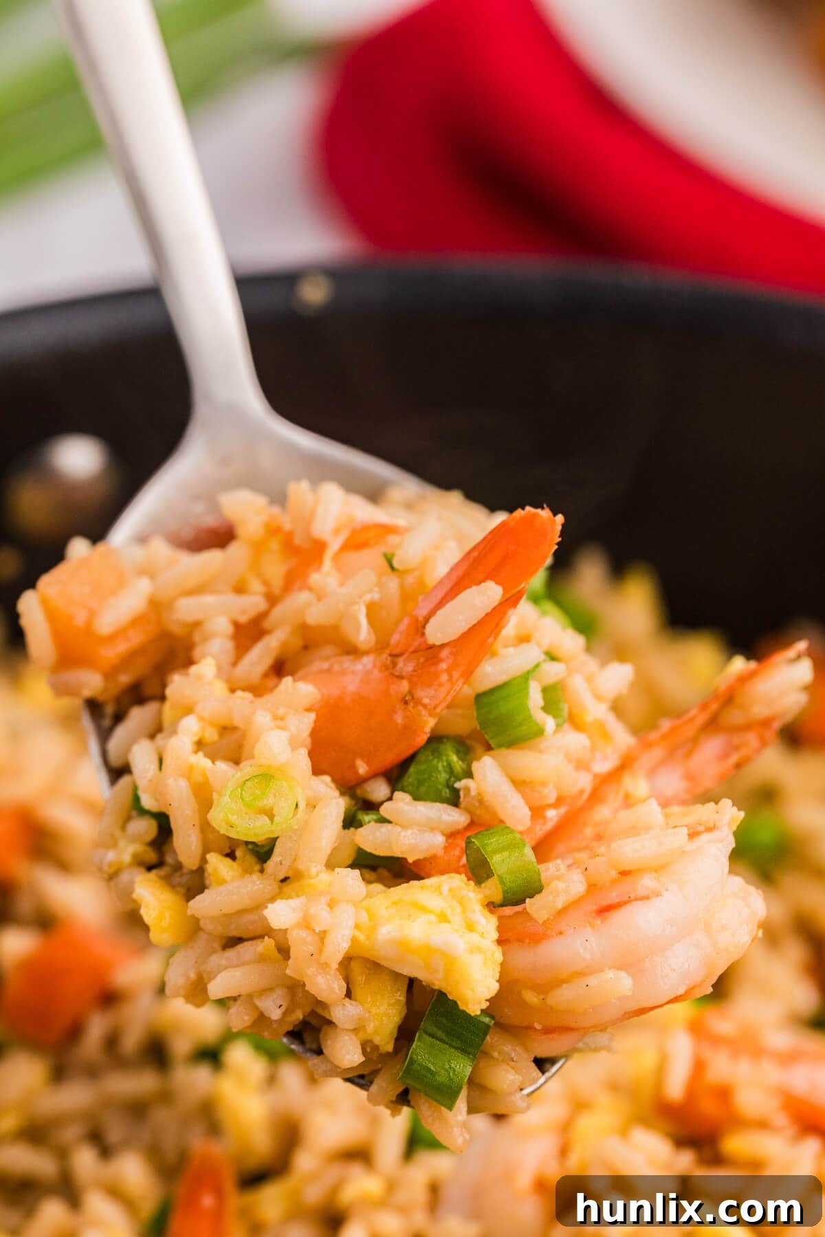 A close-up of shrimp fried rice on a serving spoon, highlighting the individual grains of rice and tender shrimp.