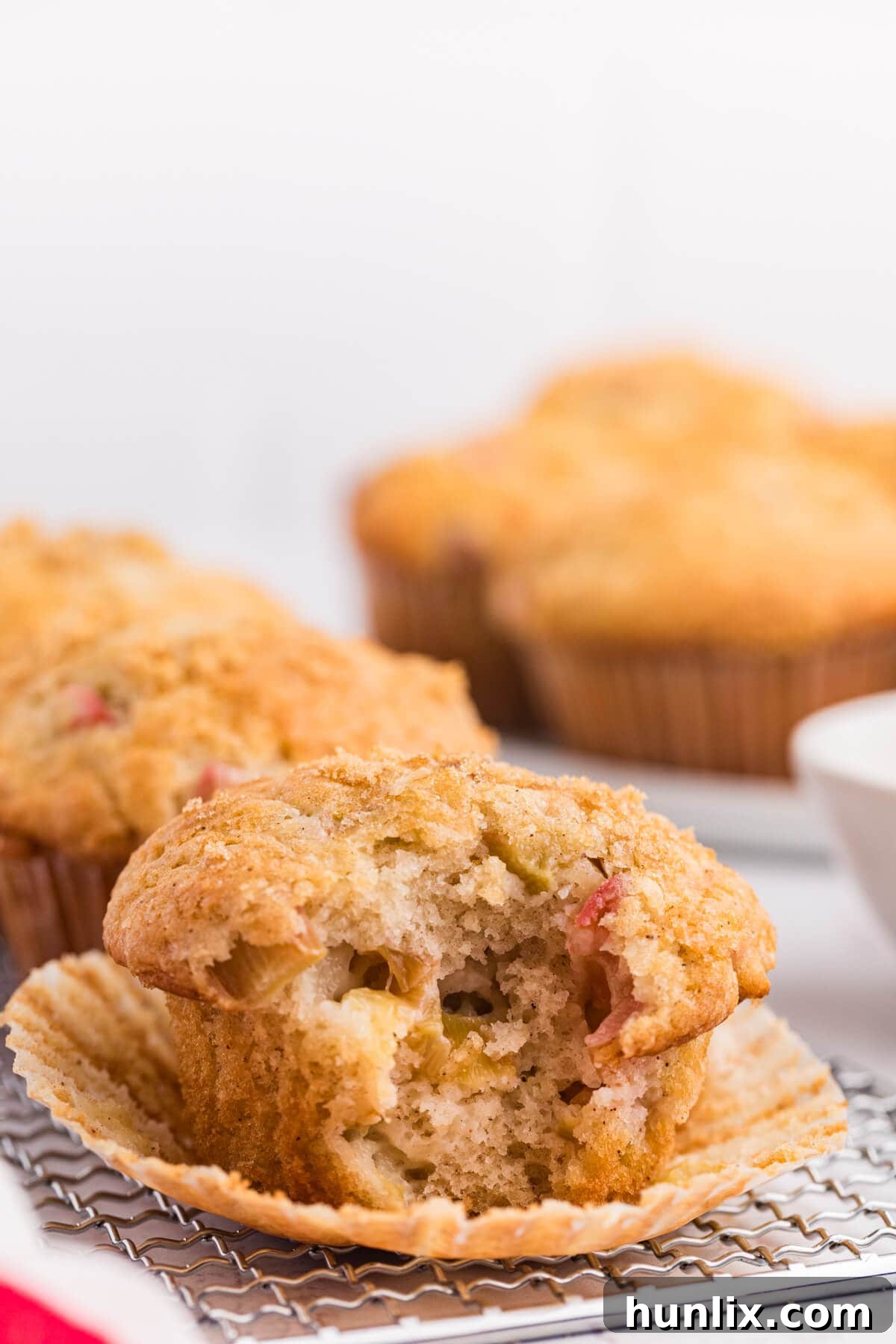 A rhubarb muffin with a bite taken out, showing its moist interior and fruit pieces.