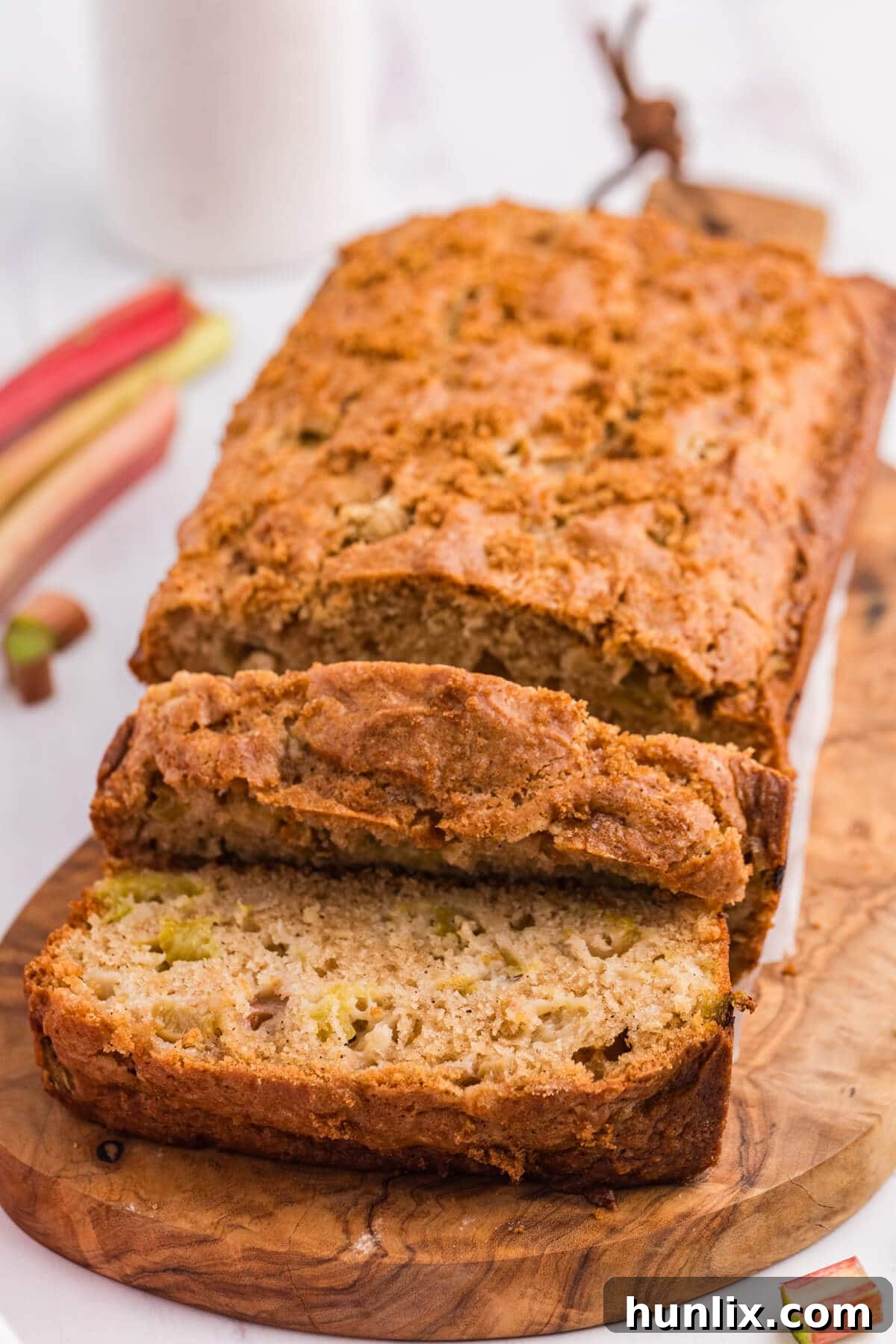 Tangy Rhubarb Loaf 2 A loaf of rhubarb bread on a wooden cutting board with a couple slices cut off the end. This moist and flavorful Rhubarb Bread is the perfect mix of sweet and tangy—made with fresh rhubarb and simple pantry staples. A delicious way to use up extra rhubarb!