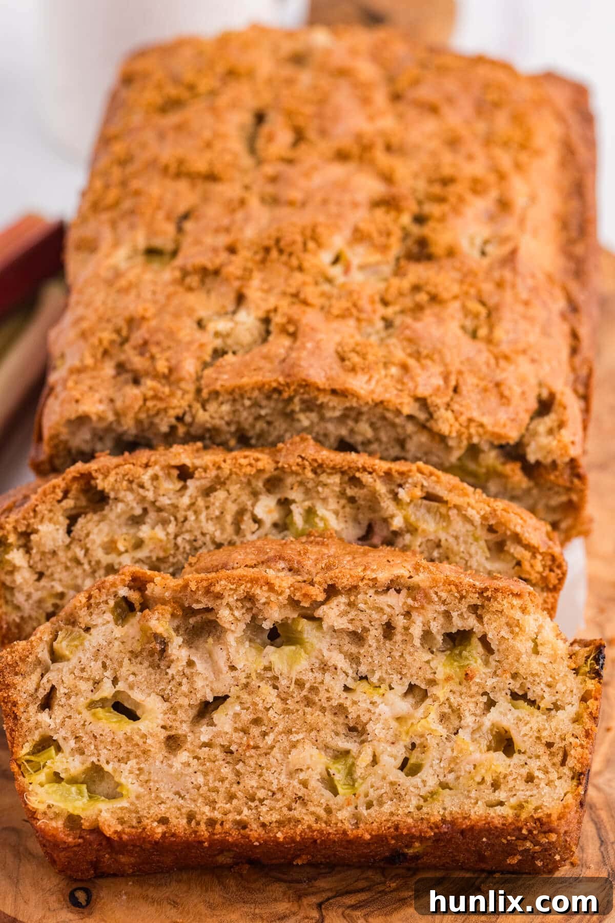 Tangy Rhubarb Loaf 8 Slices of rhubarb bread cut off a loaf, showing the moist texture and chunks of rhubarb.