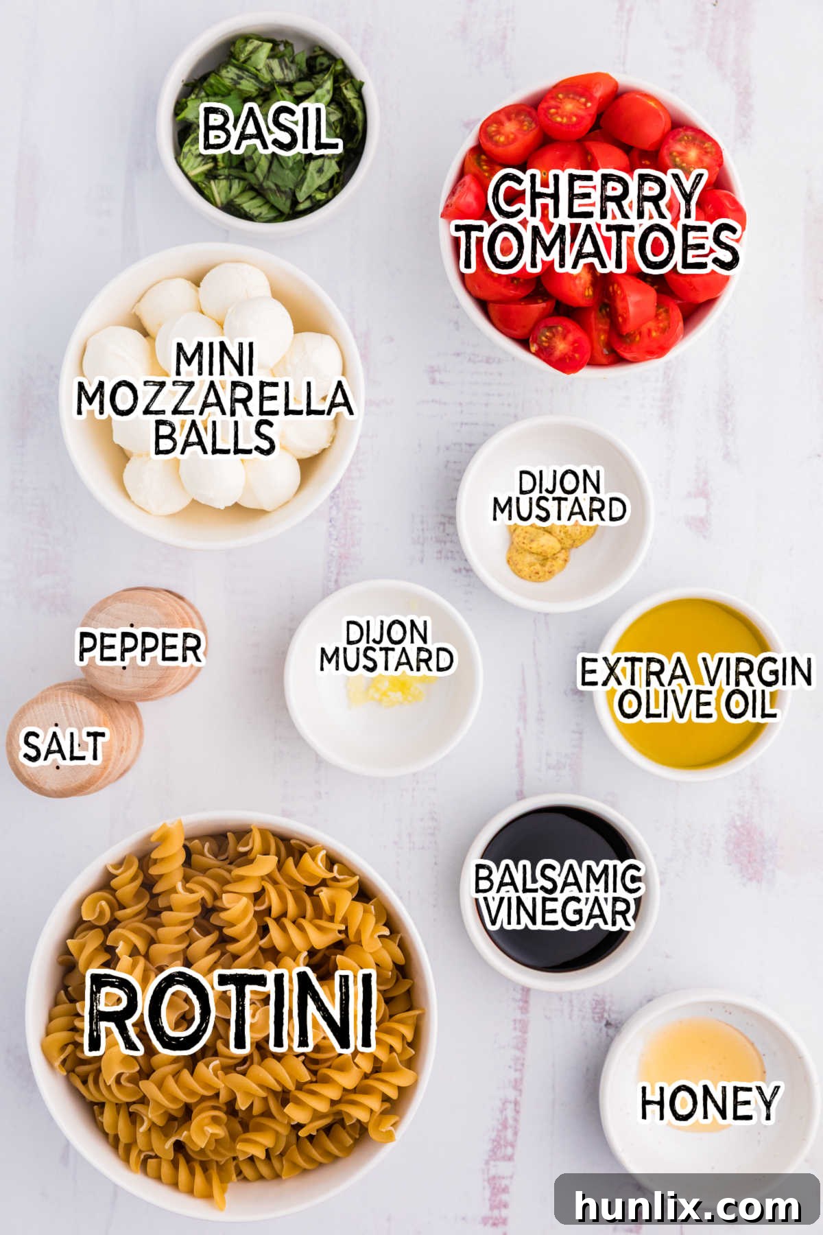 All the fresh ingredients for Caprese Pasta Salad laid out on a white surface, ready for preparation.