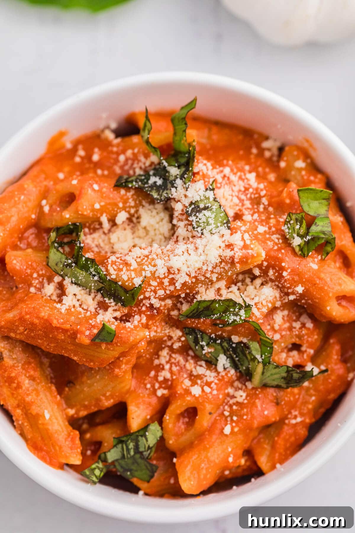 A portion of One-Pot Creamy Tomato Pasta served in a pristine white bowl, garnished with fresh herbs and a sprinkle of Parmesan cheese.