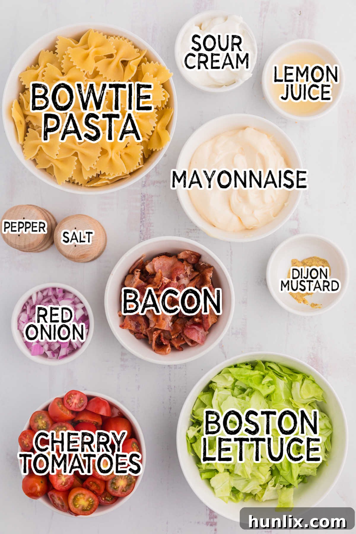 Ingredients for BLT pasta salad laid out on a white surface.