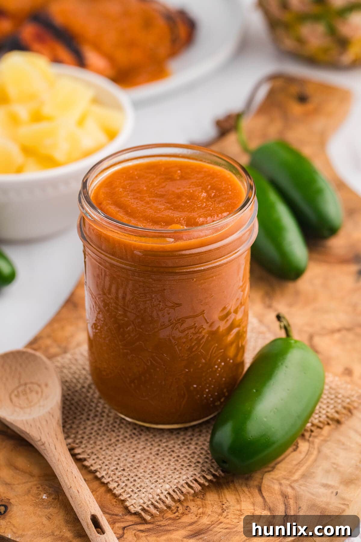 Sweet Heat Pineapple Jalapeno BBQ 2 A jar of homemade Pineapple Jalapeño BBQ Sauce with a wooden spoon.