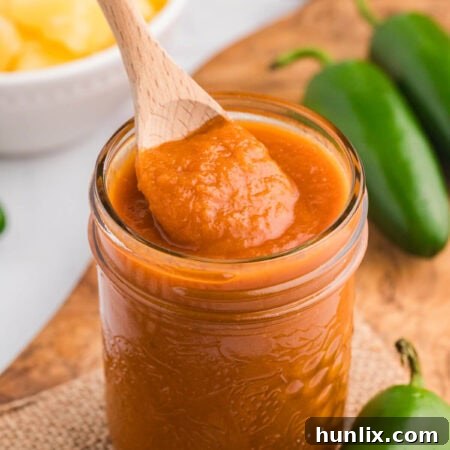 A jar of the Pineapple Jalapeño BBQ Sauce with a wooden spoon.