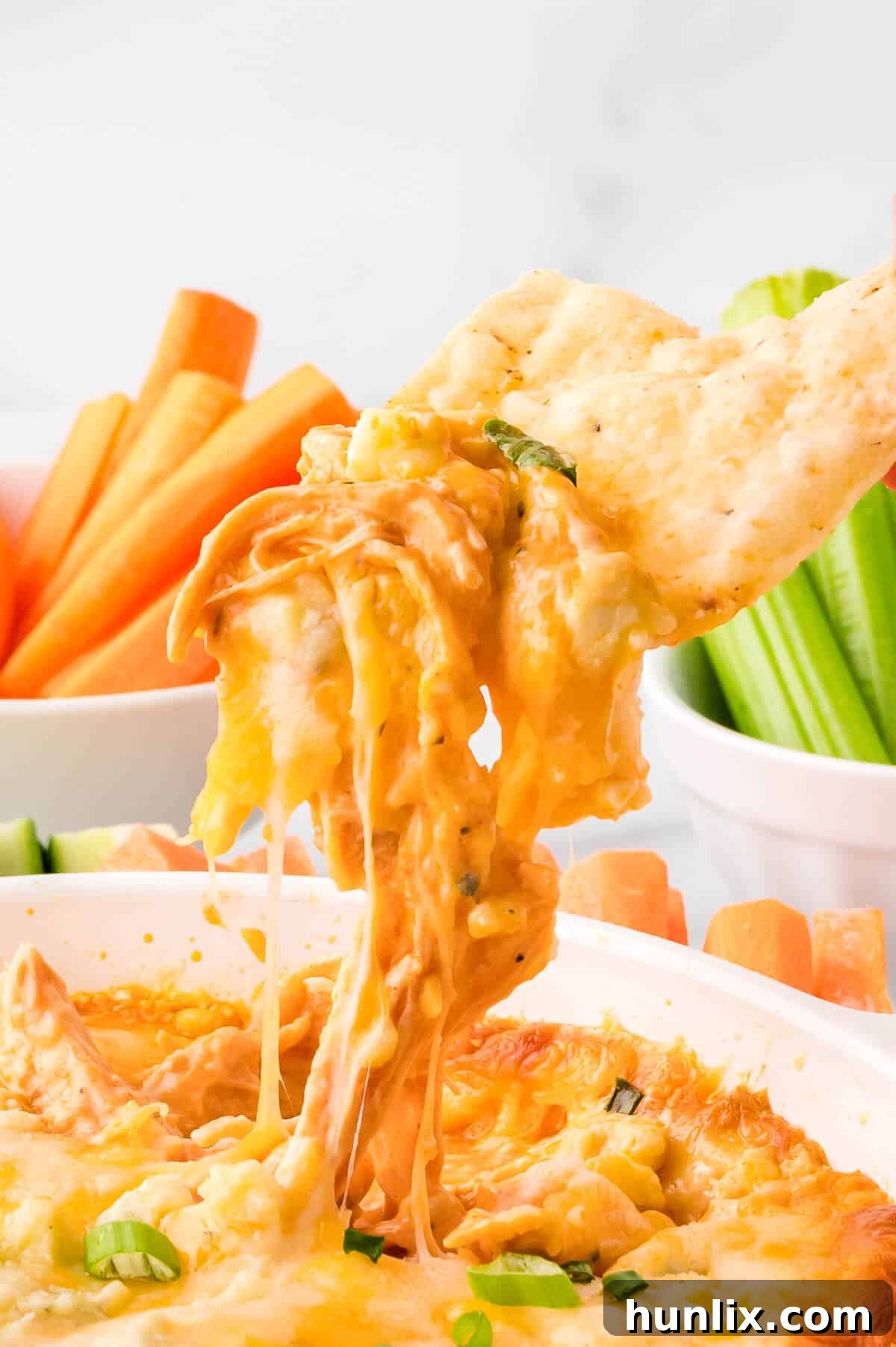 The Hot Dips You Won't Believe You Lived Without 4 A crispy tortilla chip generously scooping up creamy Buffalo Chicken Dip, flecked with chicken.