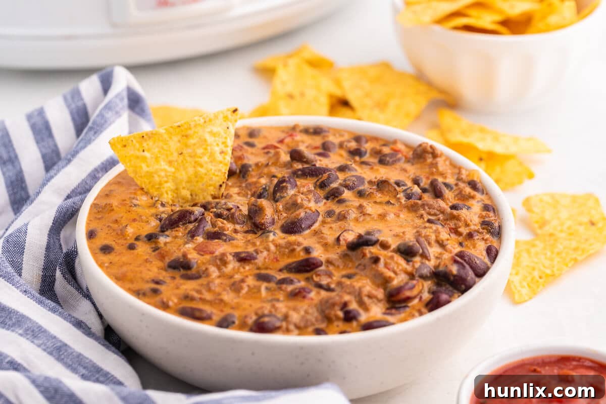 The Hot Dips You Won't Believe You Lived Without 6 A close-up of a bubbling Slow Cooker Chili Cheese Dip, rich with melted cheese and chili, garnished with fresh cilantro.