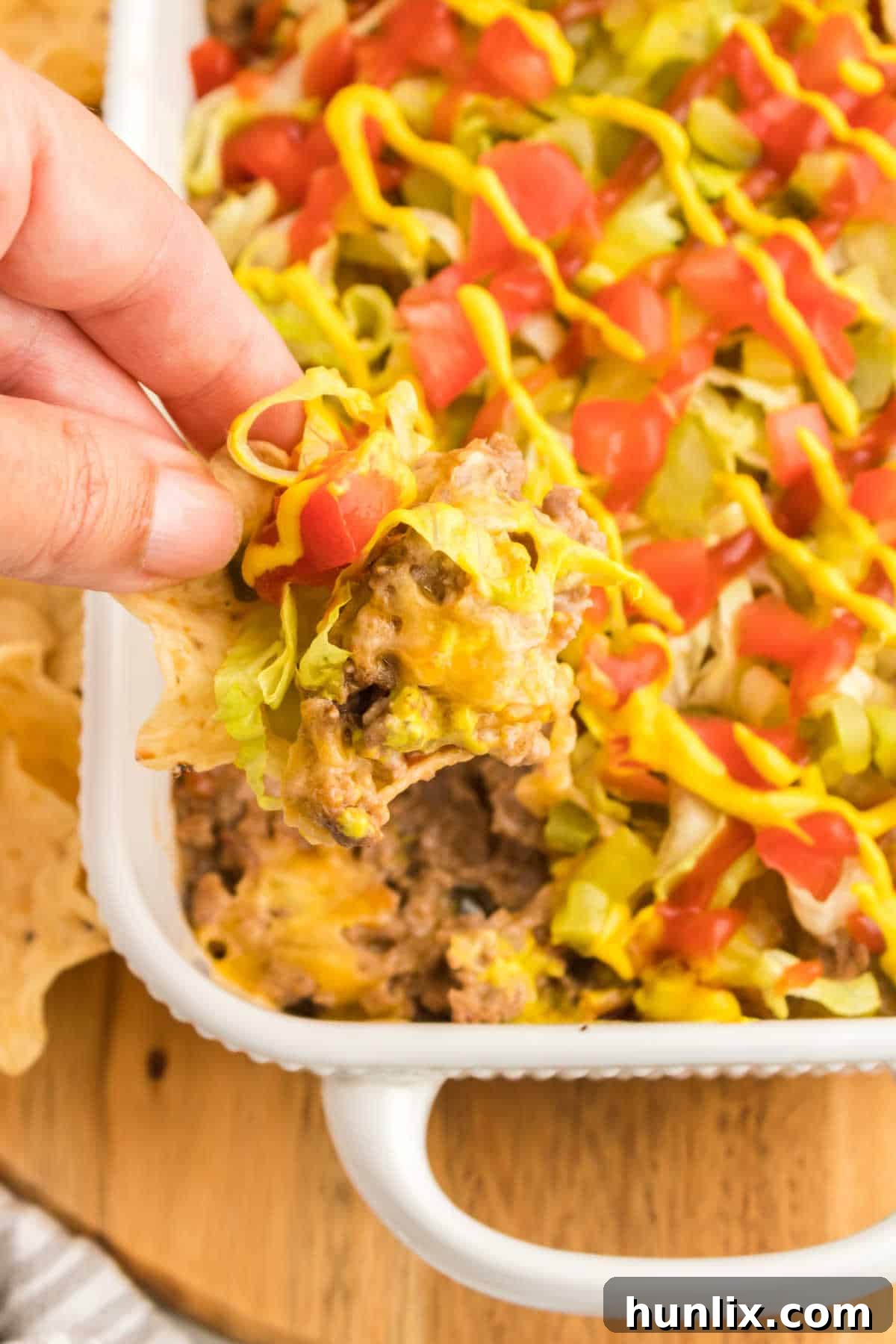 The Hot Dips You Won't Believe You Lived Without 7 A hot and cheesy cheeseburger dip in a rustic serving dish, topped with fresh green onions.