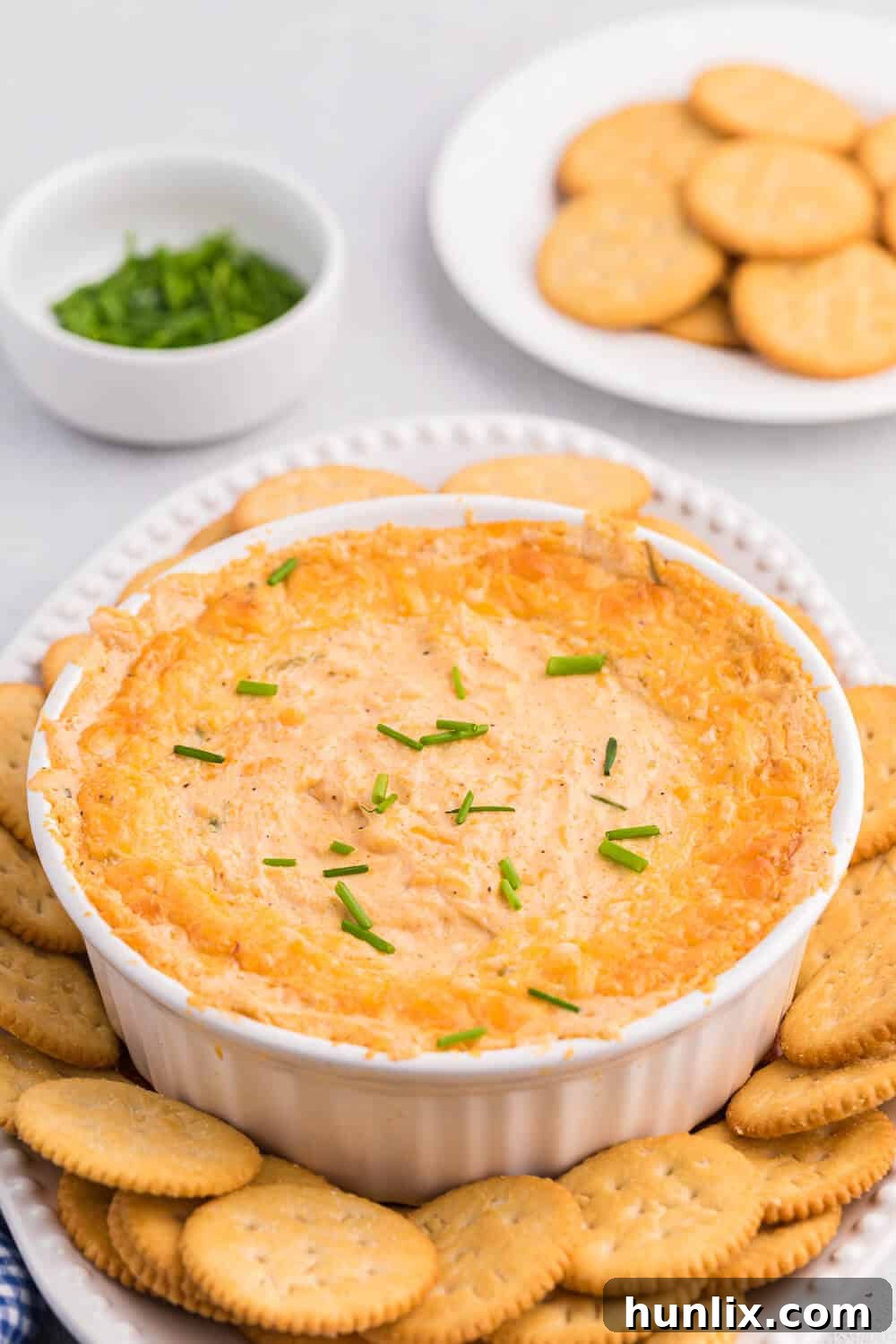 The Hot Dips You Won't Believe You Lived Without 8 A creamy, bubbly hot crab dip in a white serving dish, garnished with fresh parsley.