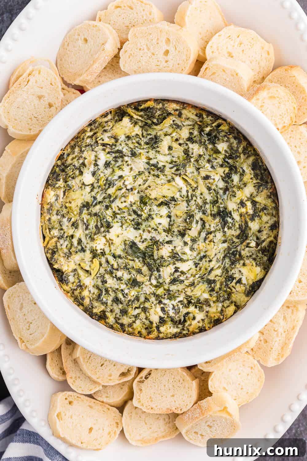 The Hot Dips You Won't Believe You Lived Without 9 A hot, bubbly spinach artichoke dip with melted cheese on top, served with toasted bread slices.