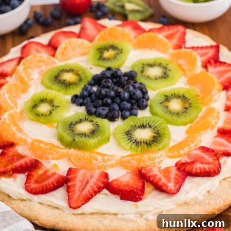 The finished Fruit Pizza on a wooden surface, ready to be served, showcasing the beautiful arrangement of fresh fruit.