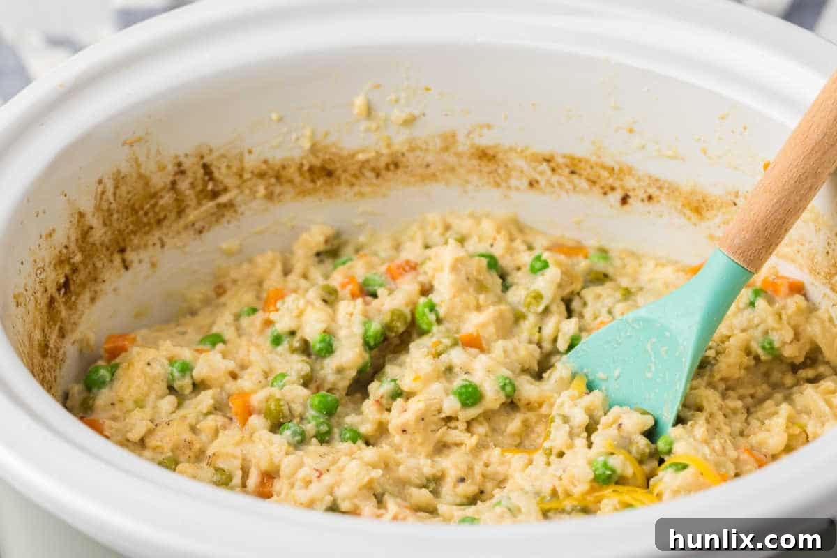 The recipe in a crockpot with a wooden spoon, featuring comforting Crockpot Chicken and Rice.