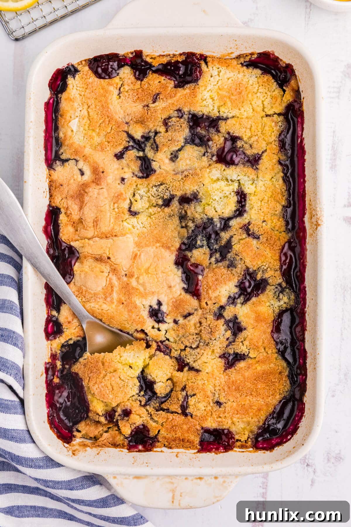 Lemon blueberry dump cake in a pan on a white surface.