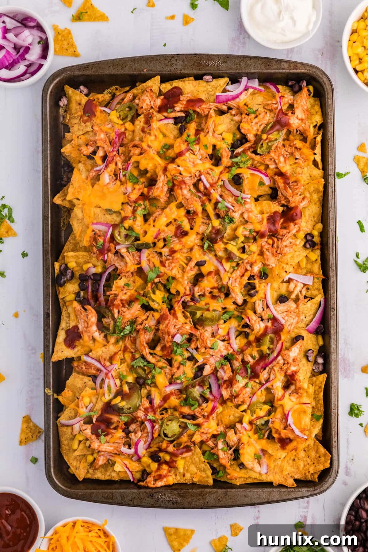 BBQ Chicken Nachos on a sheet pan on a white surface.
