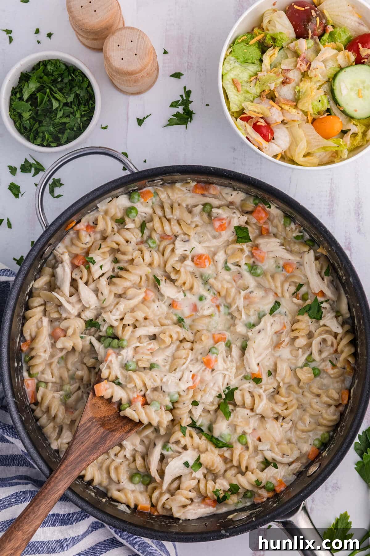 Chicken pot pie pasta in a skillet with a serving spoon.
