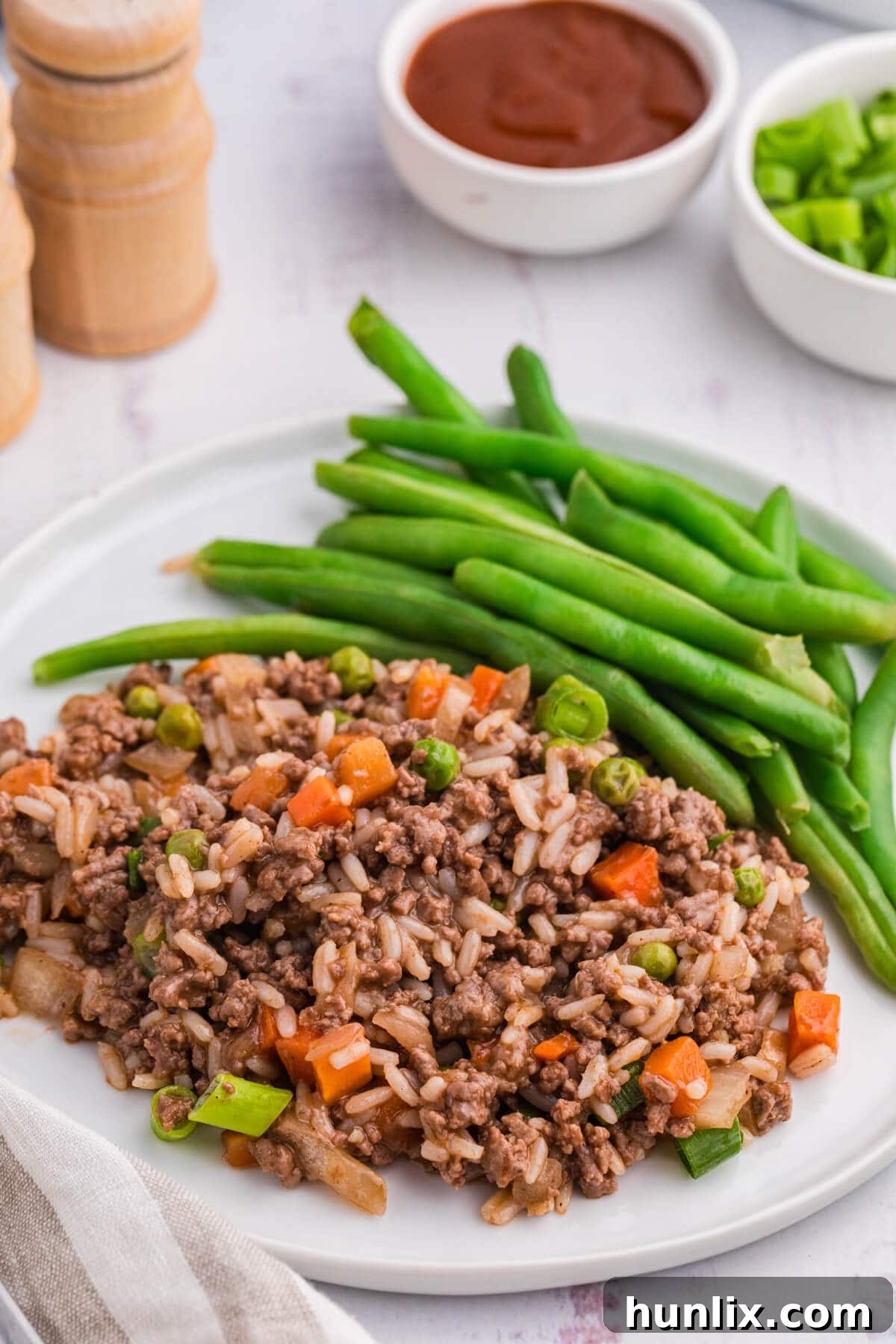 Easy Skillet BBQ Beef and Rice 7 A portion of the Skillet BBQ Beef and Rice served on a white plate with green beans as a side.