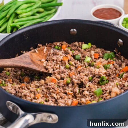 Easy Skillet BBQ Beef and Rice 8 The recipe in a skillet with a wooden spoon.