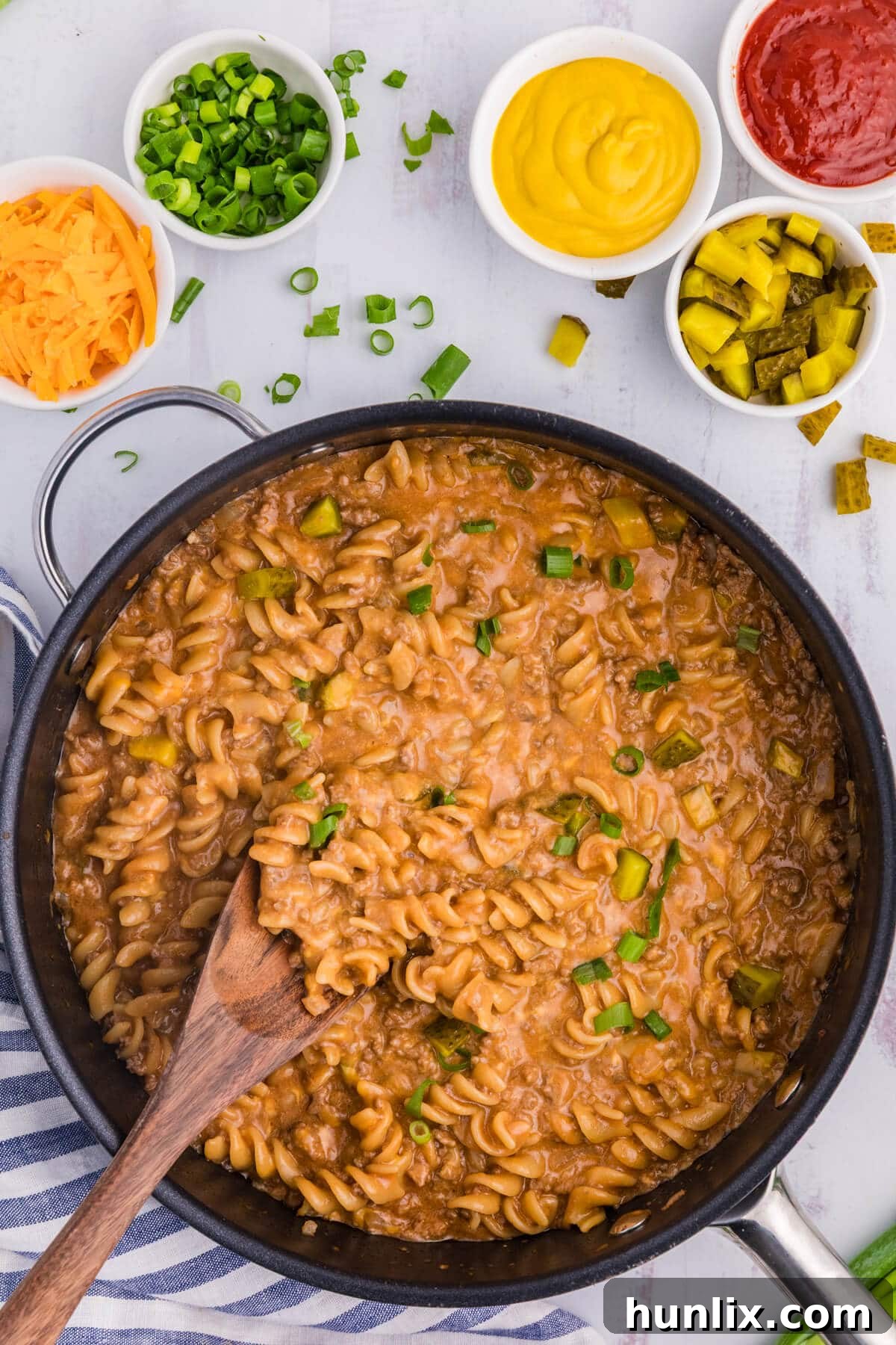 The finished cheeseburger pasta skillet with a wooden spoon, ready to be served.