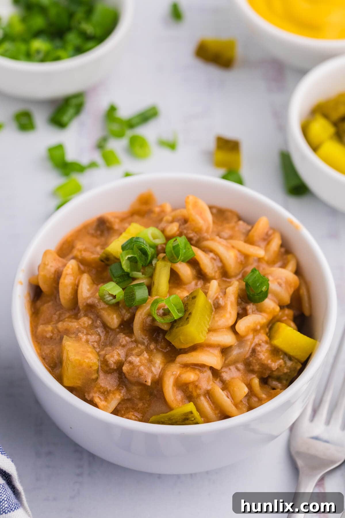 The cheeseburger pasta skillet recipe served in a white bowl, garnished with fresh green onions.