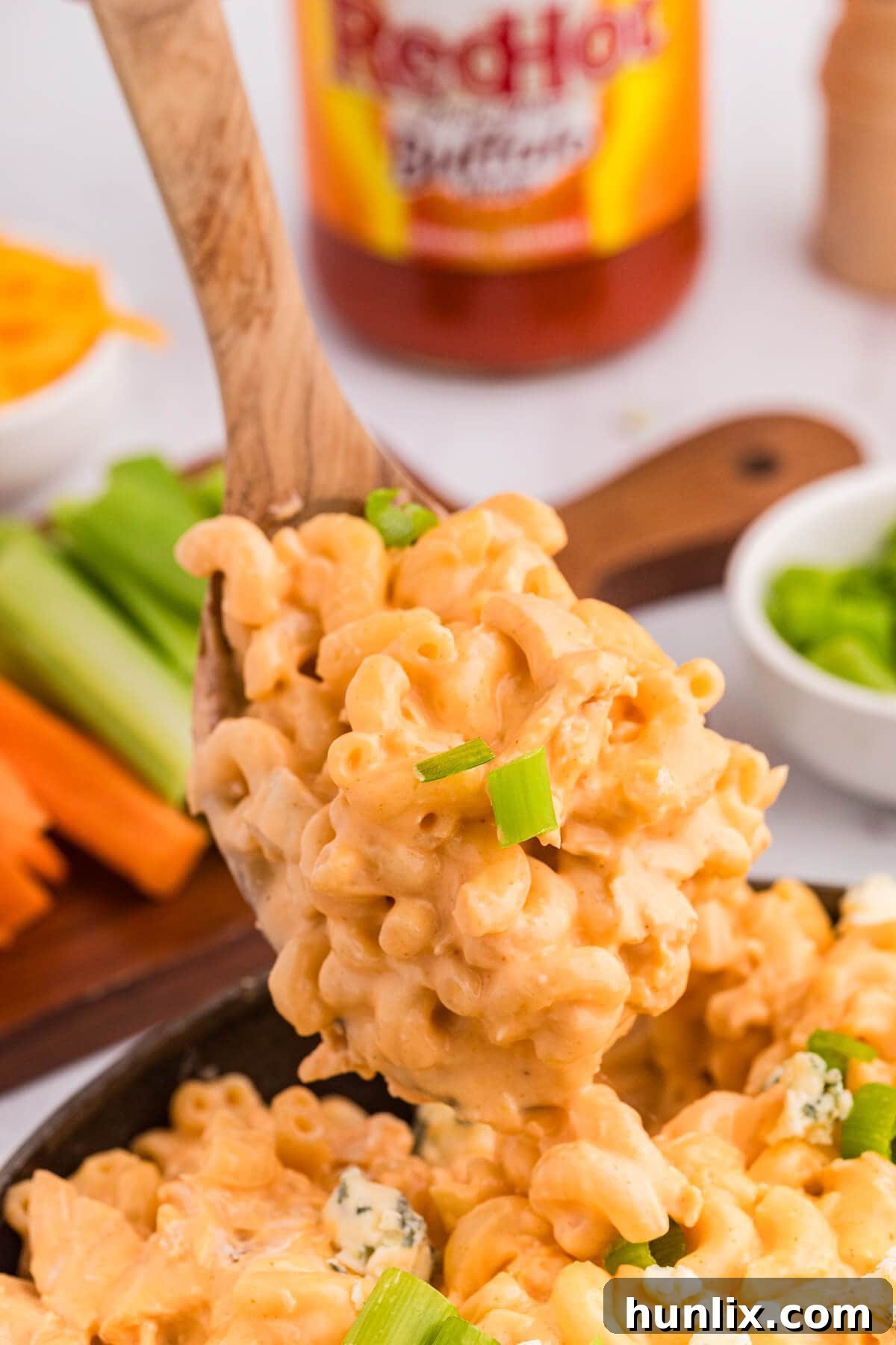 A close-up of creamy Buffalo Chicken Mac and Cheese served on a wooden spoon, showcasing the rich texture and tender chicken pieces.