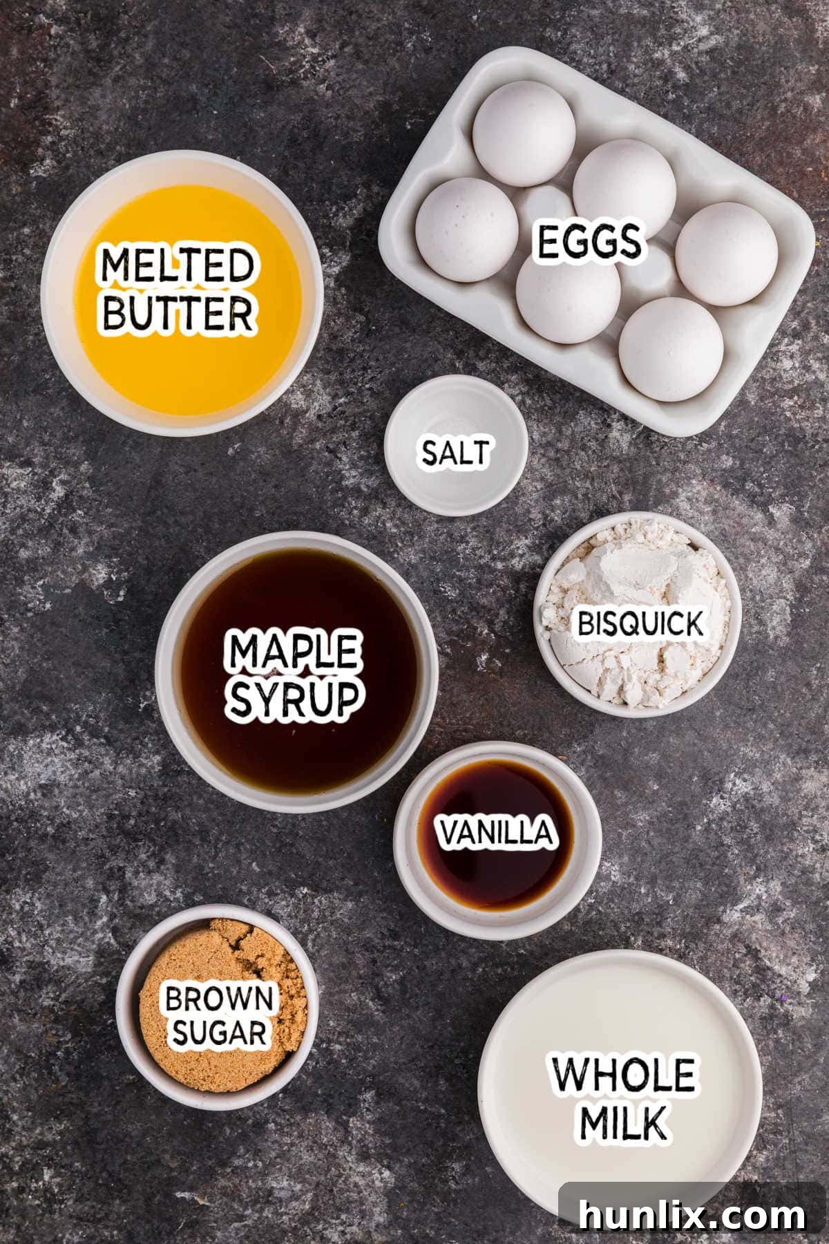 Maple Magic Pie 3 Various baking ingredients including maple syrup, brown sugar, eggs, milk, and butter arranged on a dark background.