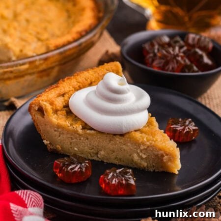 A beautiful slice of Maple Impossible Pie on a plate, topped with a generous swirl of whipped cream.