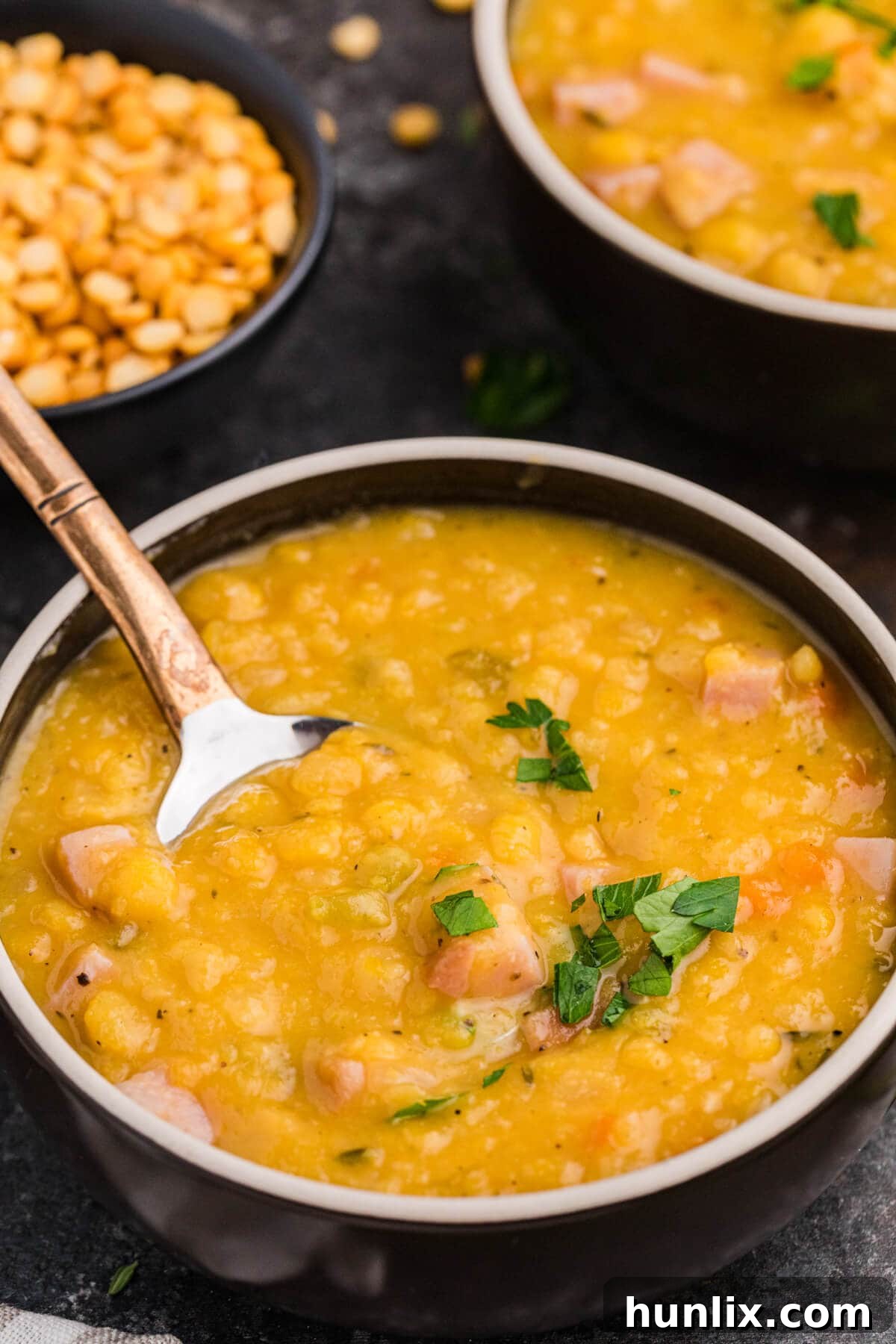 Wholesome Split Pea Warmth 6 A black bowl of split pea soup with a spoon resting in it, ready to be enjoyed.
