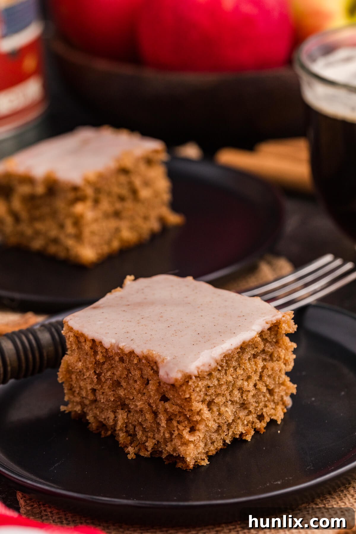 A piece of apple butter cake on a black plate with a fork, showcasing its moist texture and rich color.