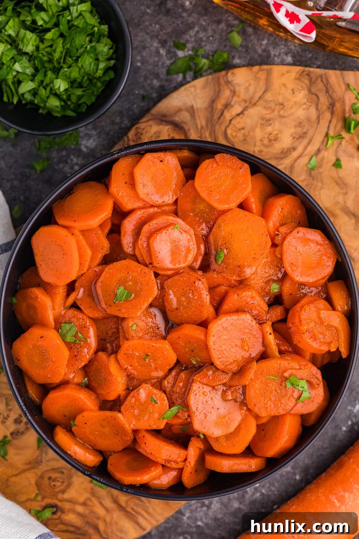 A bowl of Maple Glazed Carrots on a wooden surface.