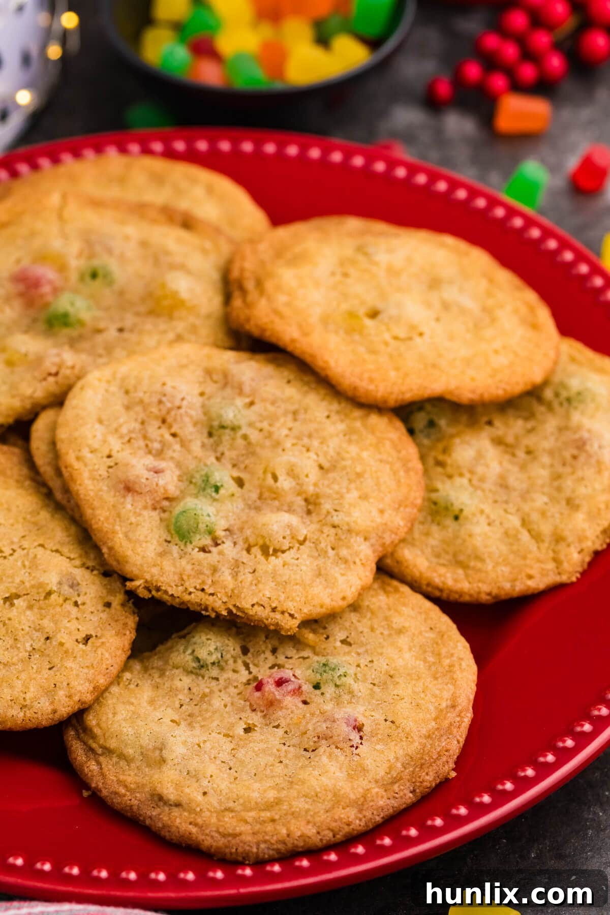 Festive Gumdrop Gems 7 Golden brown cookies with colorful gumdrop pieces on a red plate, surrounded by festive candy and holiday decor.