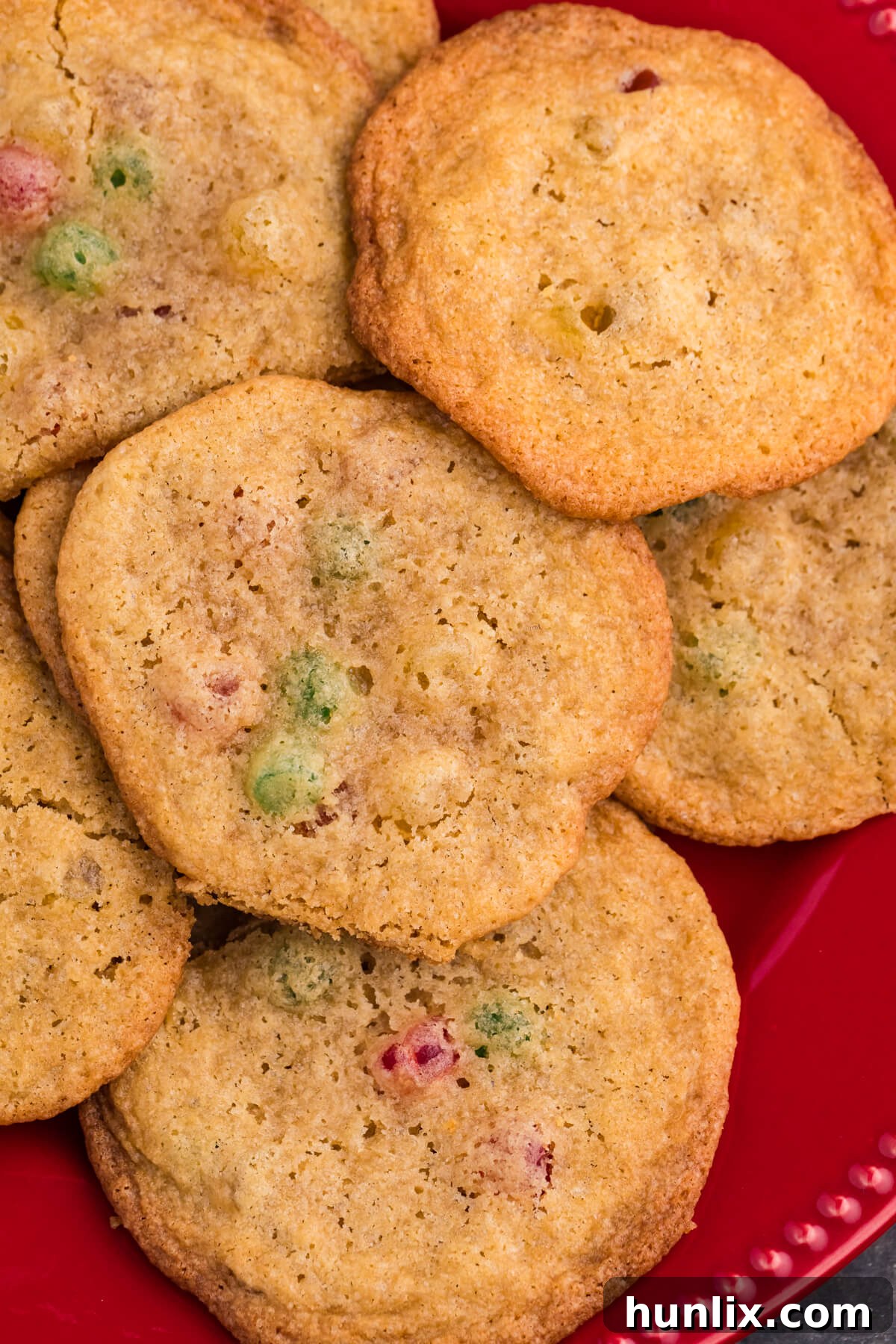 Festive Gumdrop Gems 8 Golden brown cookies with colorful gumdrop pieces on a red plate, surrounded by festive candy and holiday decor.