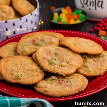 Festive Gumdrop Gems 9 Holiday cookies with colorful gumdrops arranged on a red plate, surrounded by Christmas-themed decor, a candy bowl, and a festive cookie tin in the background.