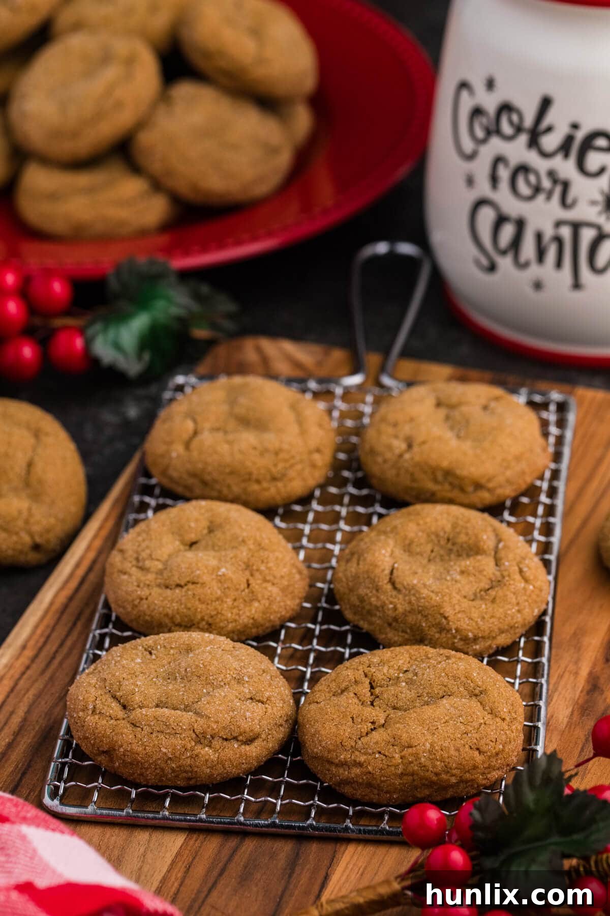 Ginger Molasses Cookies cooling on a wire rack with festive holiday decor, red berries, and a “Cookies for Santa” jar in the background.