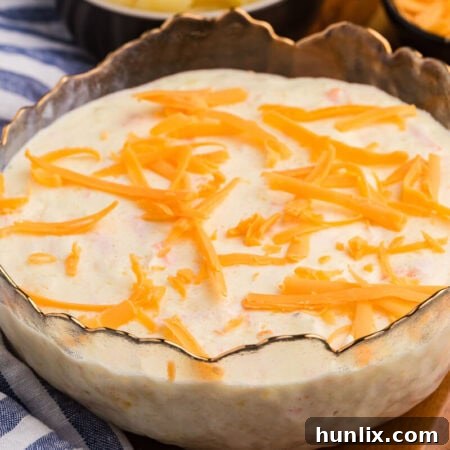Pineapple salad topped with shredded cheddar cheese, served in a decorative glass bowl.