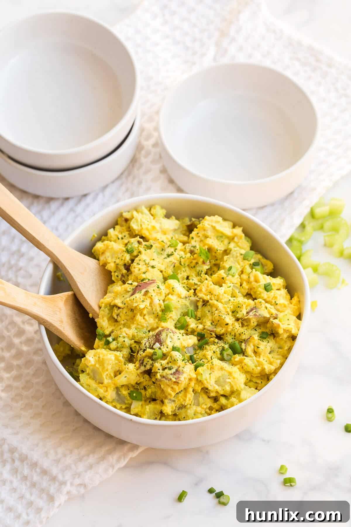 A close-up shot of curried potato salad in a bowl, showcasing the creamy texture and chopped ingredients like eggs and celery.