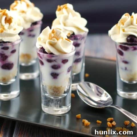 Elegant Saskatoon Berry Dessert Shooters layered with berries, mascarpone, and maple whipped cream.