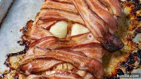 Halloween Mummy Meatloaf shaped and wrapped in bacon with onion eyes.