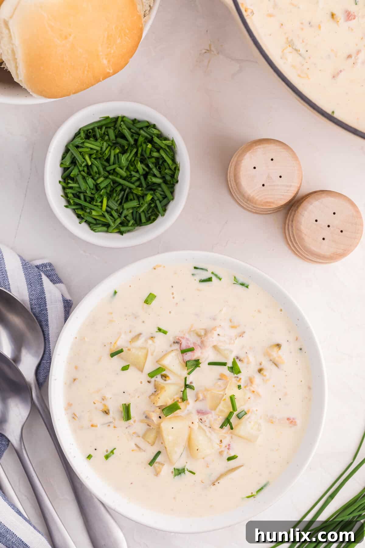 The Quintessential New England Clam Chowder 7 A classic bowl of creamy New England Clam Chowder garnished with fresh herbs and a side of oyster crackers.