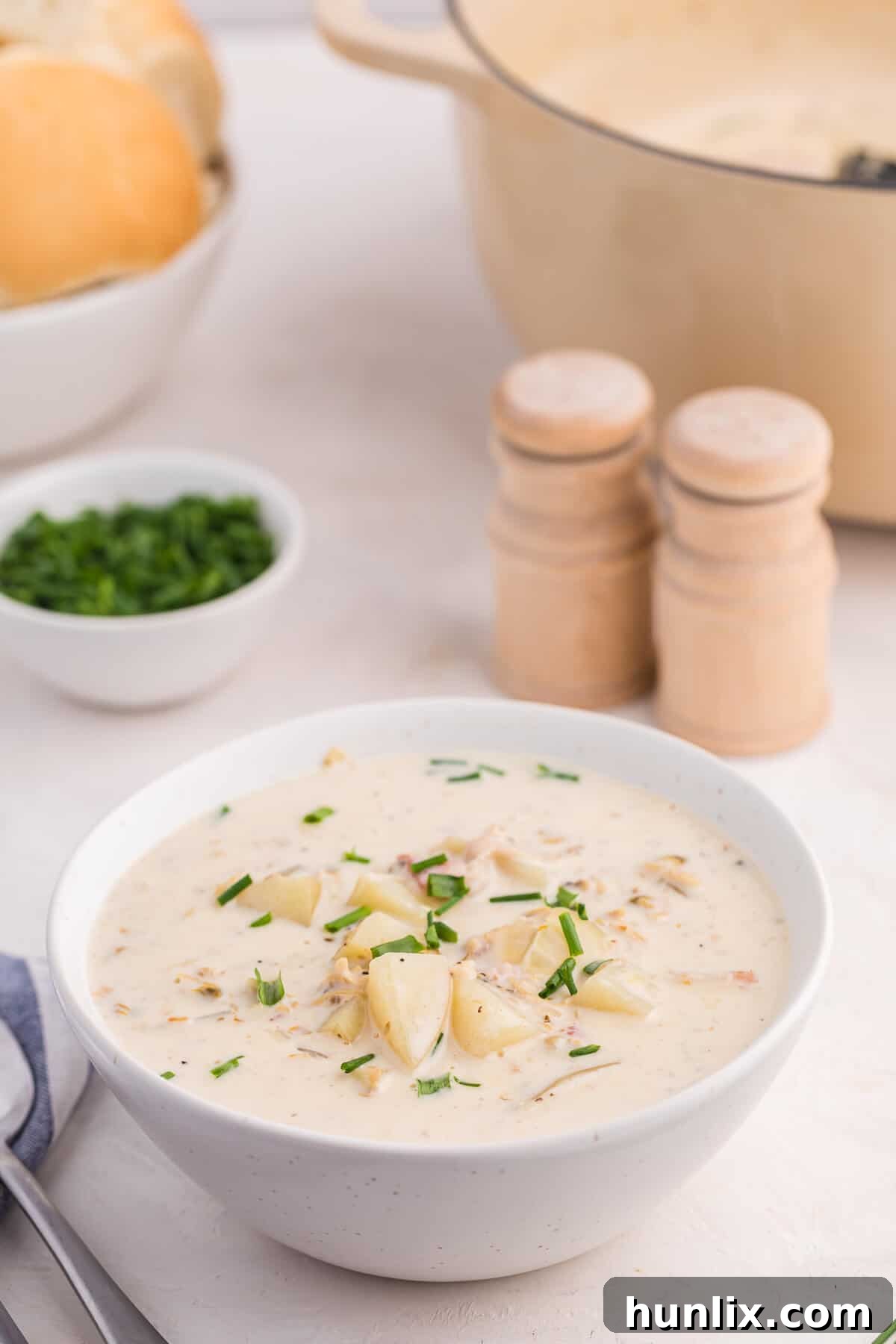 The Quintessential New England Clam Chowder 8 A close-up shot of a bowl of creamy New England Clam Chowder, garnished with fresh parsley.