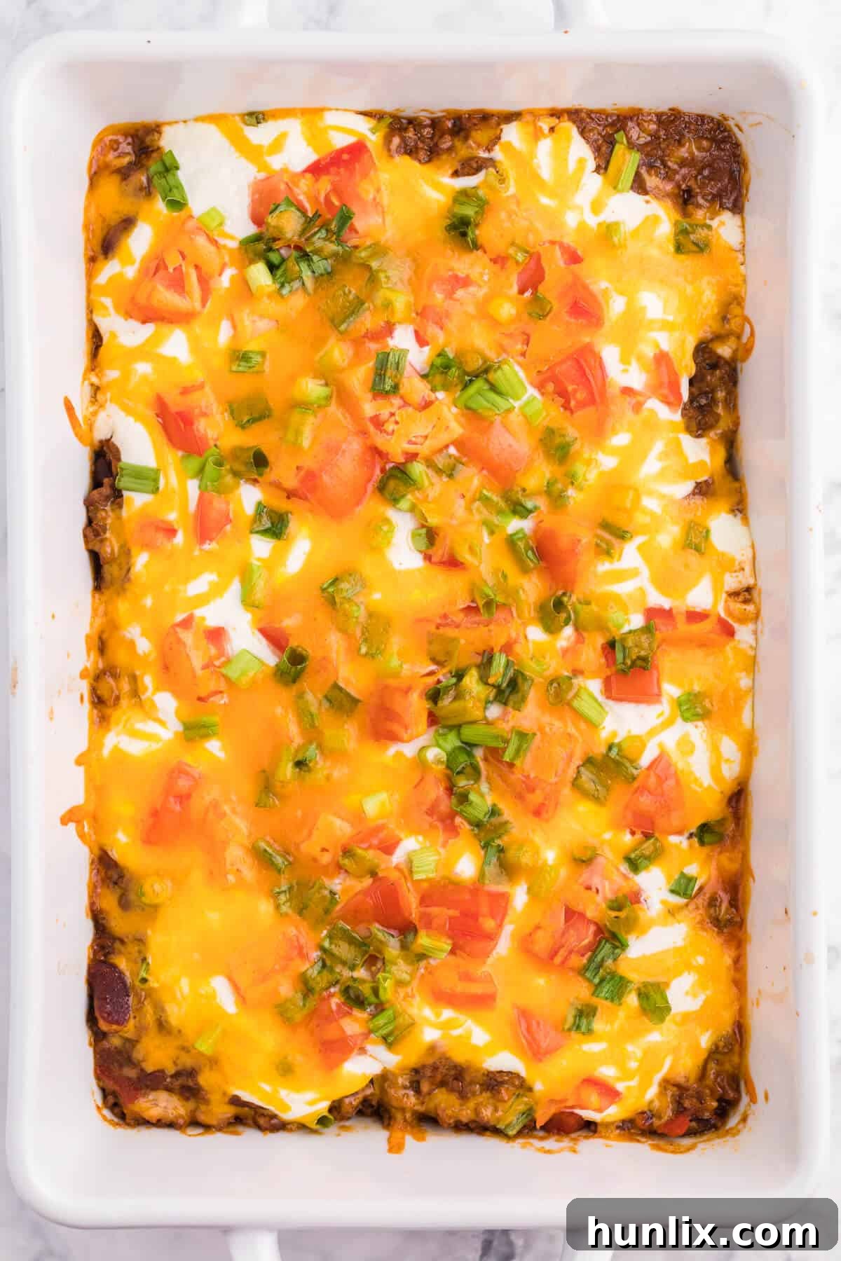 Taco casserole in a pan, garnished and ready to serve.