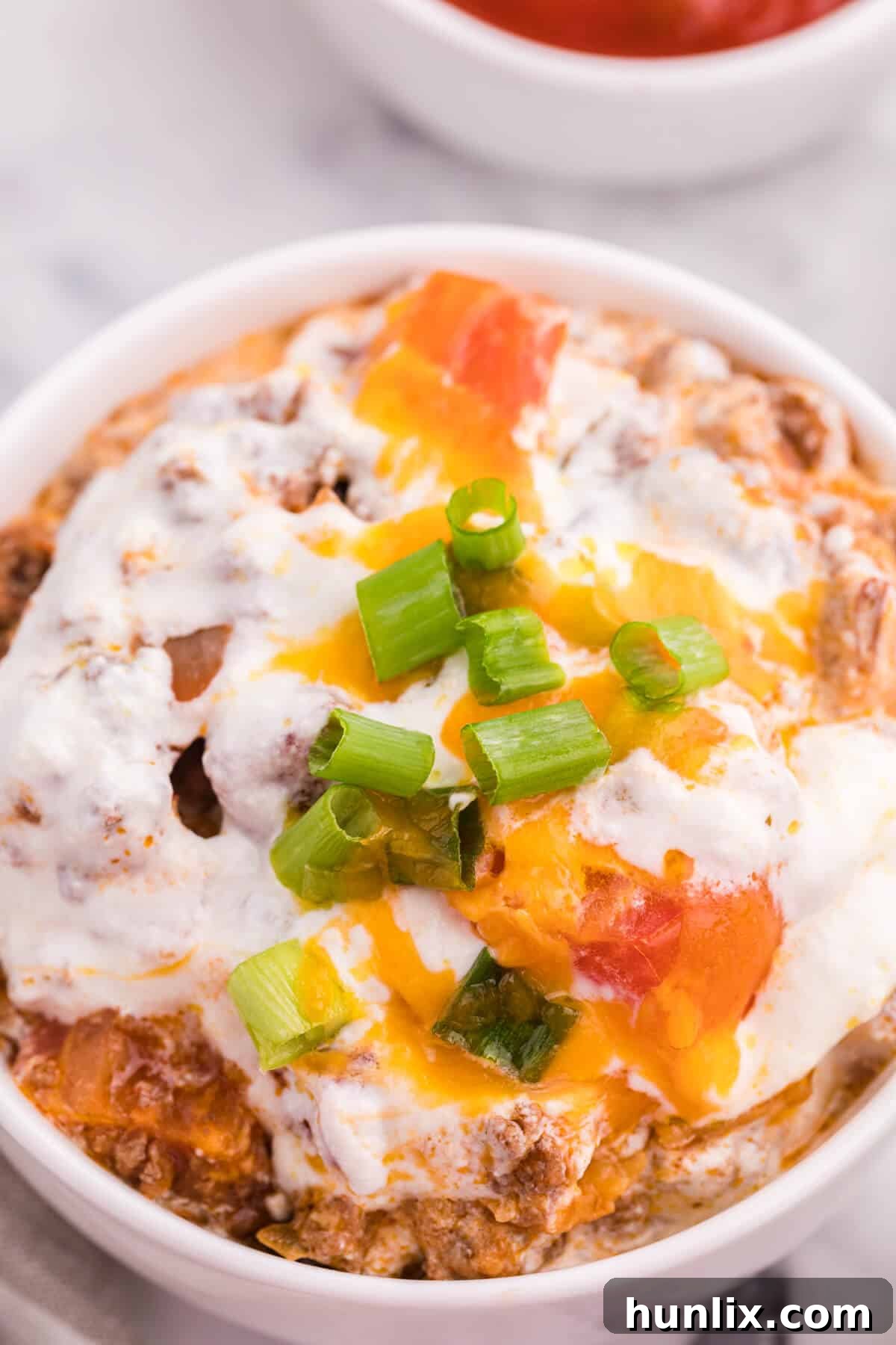 A close-up of a bowl of taco casserole, highlighting the textures and ingredients.