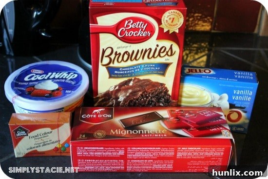 A simple layered truffle dessert with brownie, green pudding, and whipped cream in a glass cup.