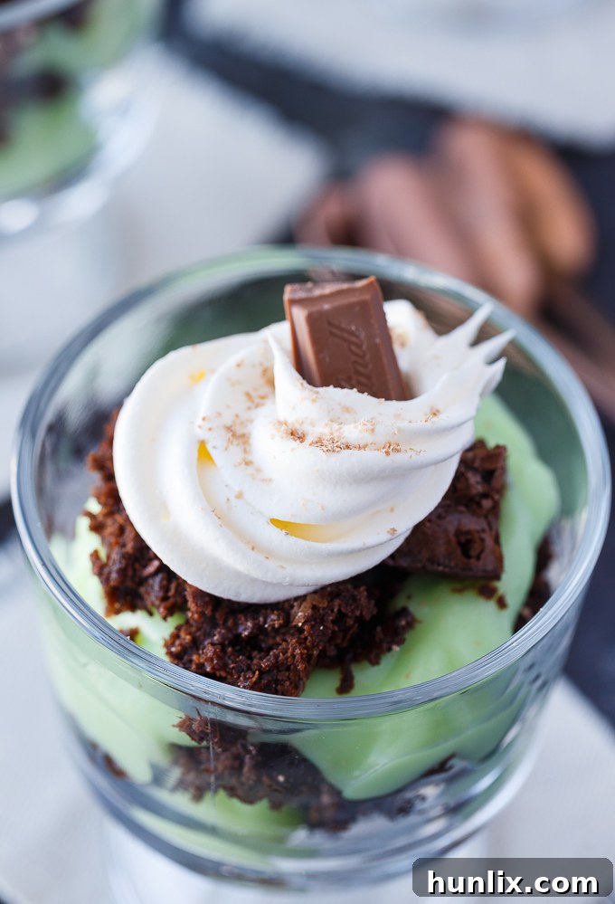 Beautifully layered St. Patrick's Day Truffles in clear glasses, garnished with whipped cream and chocolate.