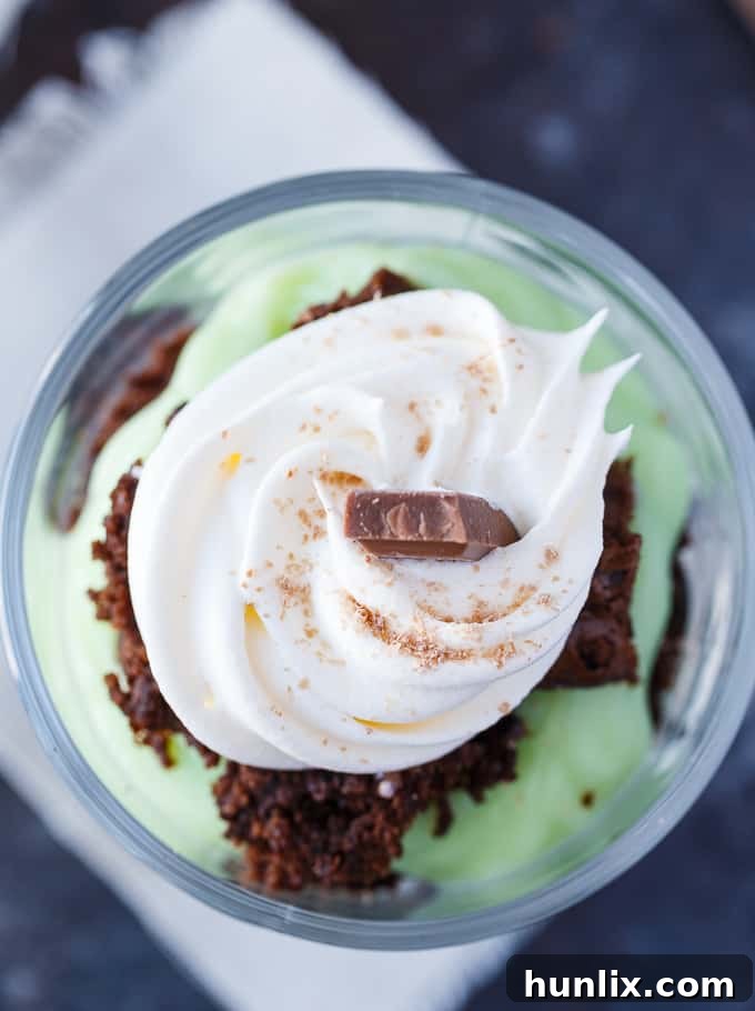 Close-up of a St. Patrick's Day Truffle in a clear glass, showing the layers of brownie, green pudding, and whipped topping.