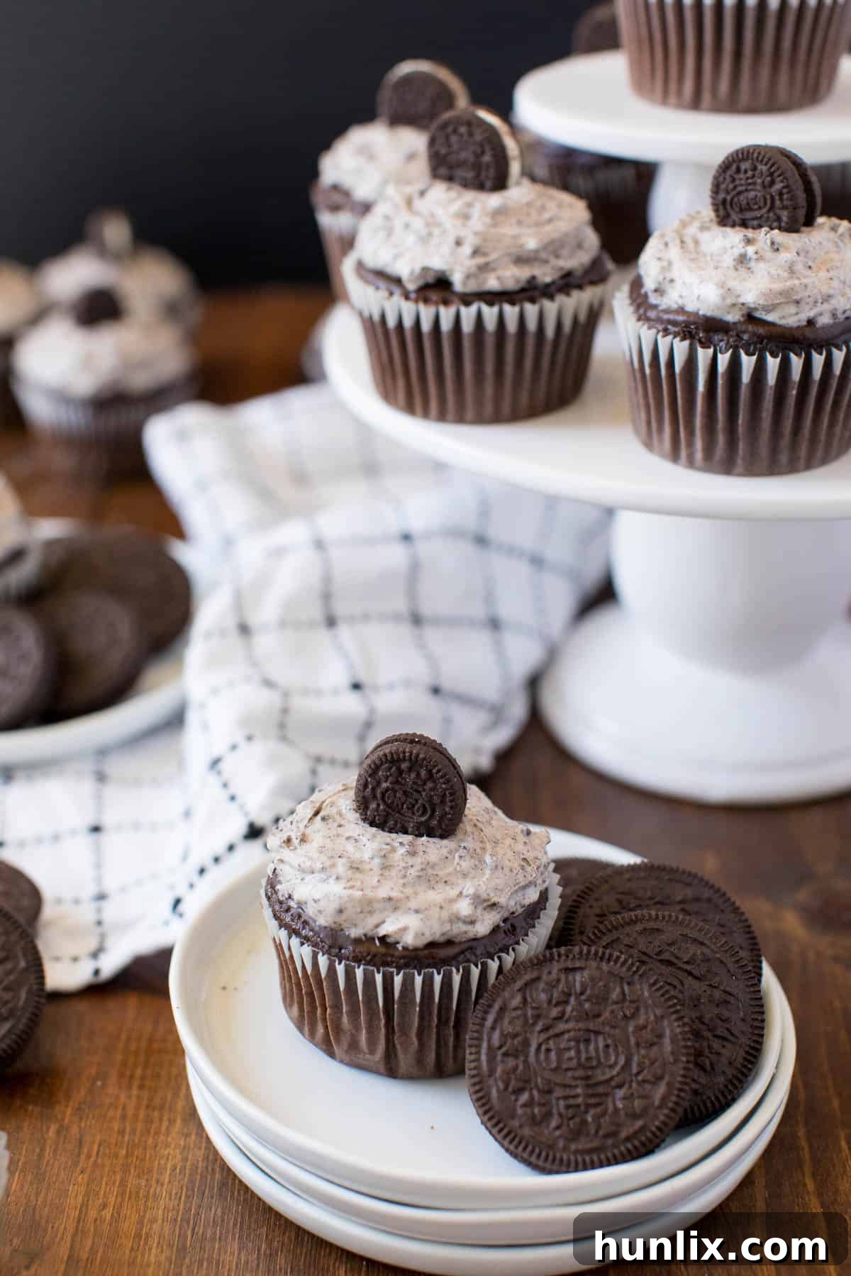 A beautifully decorated Oreo cupcake on a plate, surrounded by whole Oreo cookies, emphasizing its appeal.