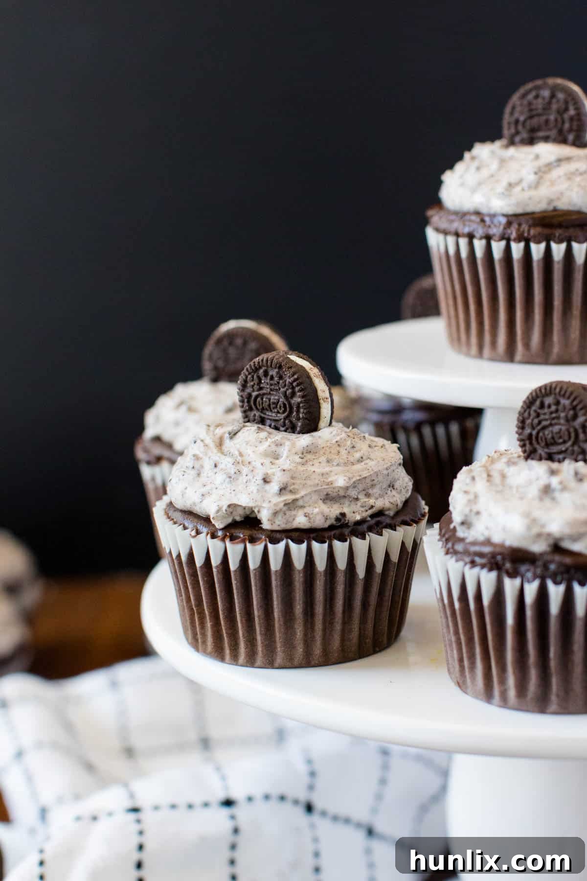 Several frosted Oreo cupcakes arranged neatly on a white cupcake stand, ready to be enjoyed.