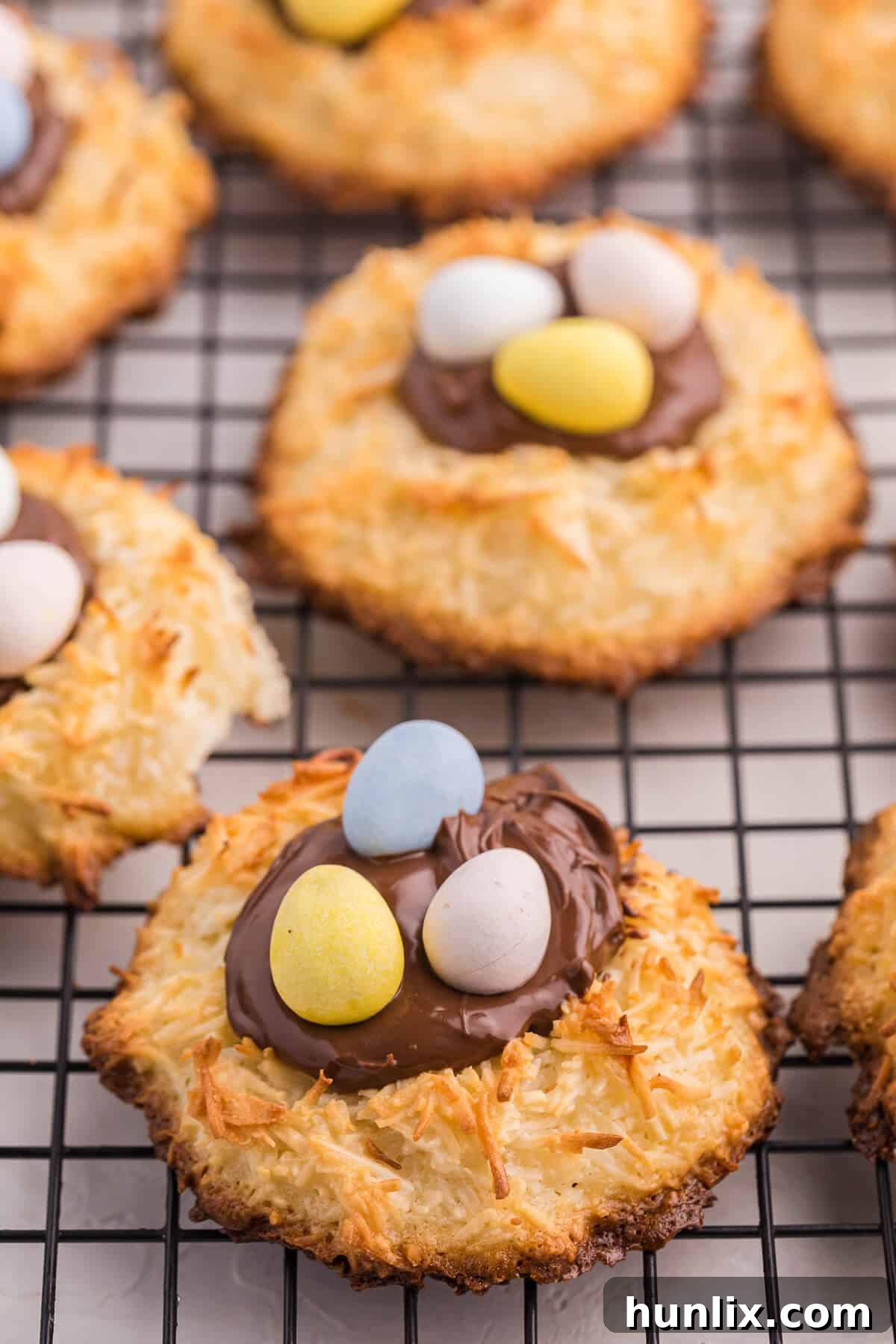 Freshly baked Coconut Macaroon Nutella Cookie Nests cooling on a rack, awaiting their Nutella and candy egg toppings.