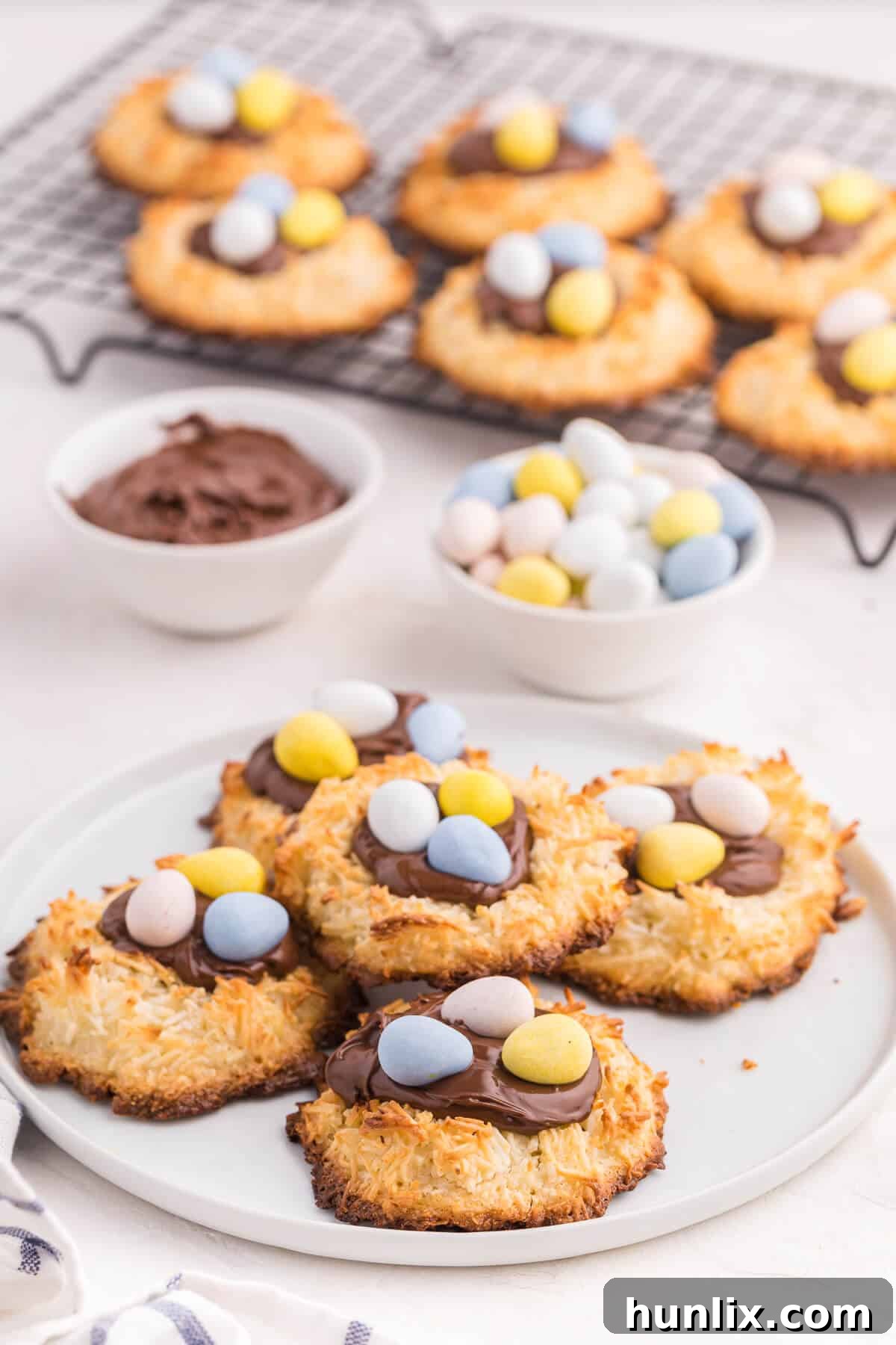 A close-up of a Coconut Macaroon Nutella Cookie Nest on a white plate, showing the Nutella and mini Easter eggs.