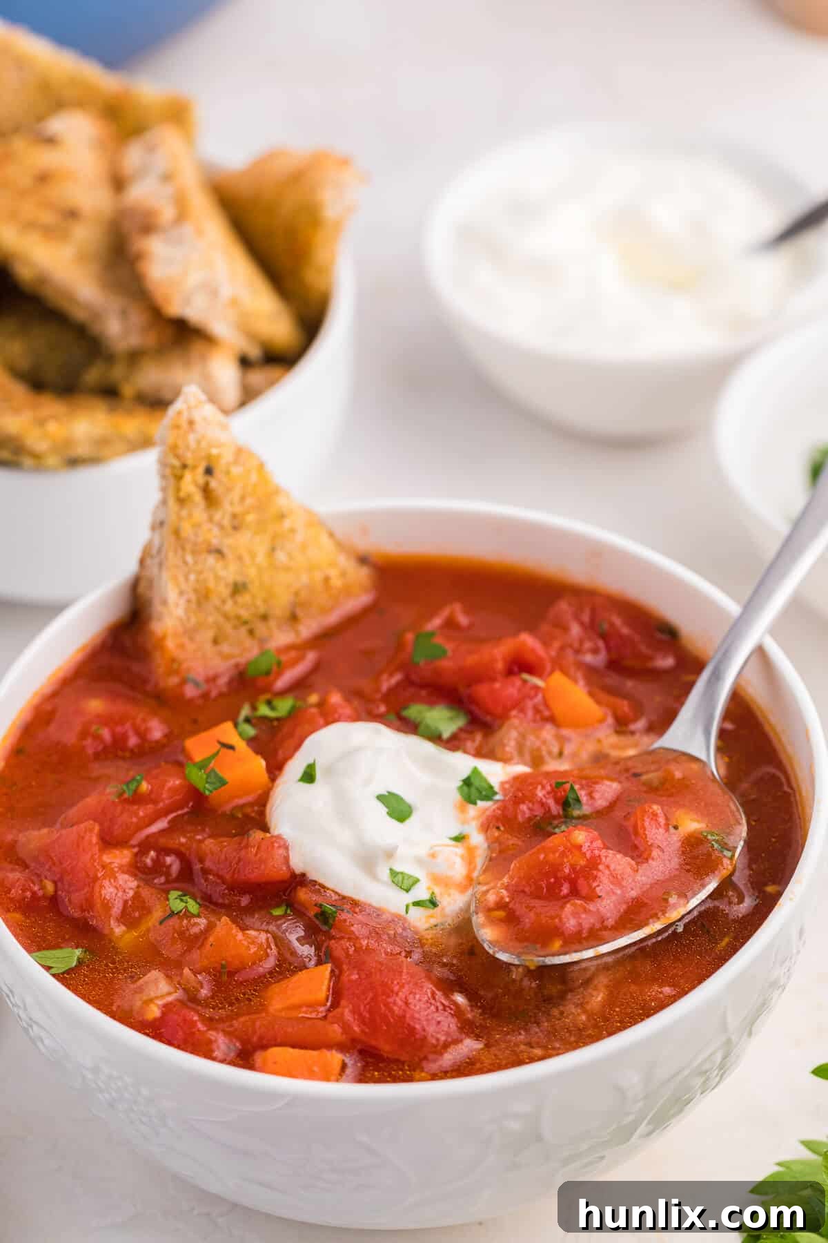 Tuscan Herb Medley Soup 6 A bowl of Italian herb soup with a spoon and several pieces of garlic toast, ready to be enjoyed.
